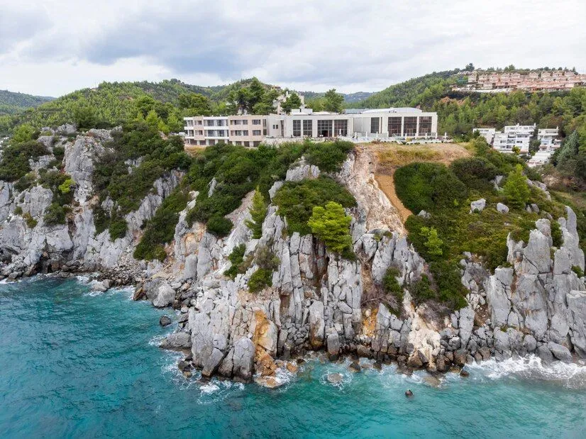 aegean-sea-coast-greece-loutra-buildings-located-near-rocky-cliffs-greenery-blue-water-view-from-drone_1268-16375.jpg